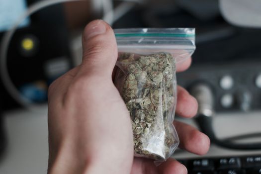Green dry marijuana in man hand on the blurry background. Weed concept.