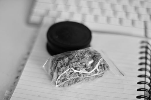 Red grinder, marijuana in big transparent bag near white computer keyboard.