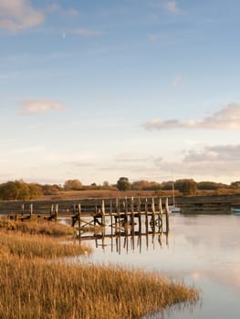 harbour pier dock wooden structure water outside boats lake river day; essex; england; uk