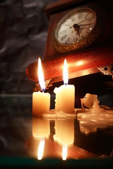 Vintage still life with lighting candles near old clock