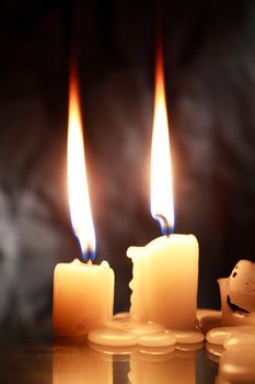 Closeup of two lighting candles against dark background