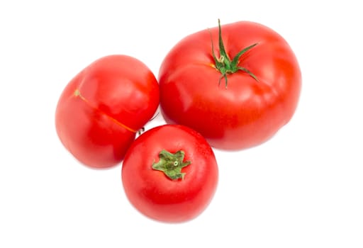 Three ripe red tomatoes different sizes closeup on a light background
