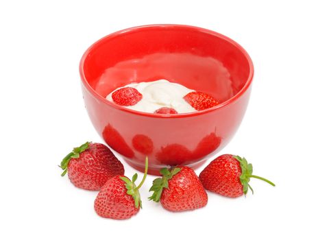 Fresh berries of the strawberry with whipped cream in red ceramic bowl and several berries separately beside on a light background
