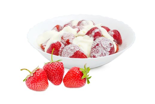 Strawberry dessert with whipped cream in white bowl and several fresh strawberry berries beside on a light background
