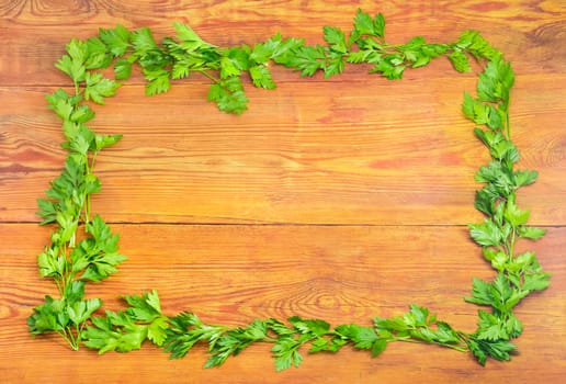 Background of the parsley twigs laid out around the perimeter in the form of a frame on old wooden planks with empty central part 
