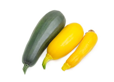 One fresh dark green zucchini and two yellow vegetable marrows on a light background
