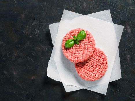 Two raw beef meat steak cutlets for burger on black concrete background with copy space. Making homemade burger concept. Top view or flat lay.