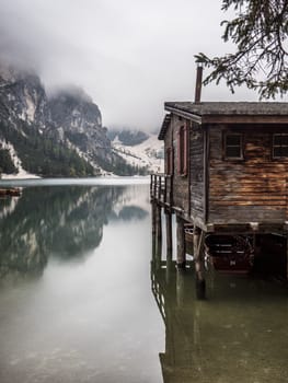 View to beautiful calm lake in forest in mountains, with a wooden hut, cabana or small house on the water