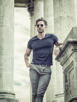 Handsome man with marble columns behind him, looking away