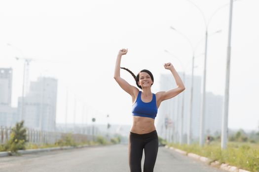 Low angle view of young female athlete crossing finish line against clear blue sky.