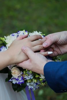 Wedding day. The groom places the ring on the bride's hand.