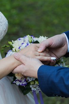 Wedding day. The groom places the ring on the bride's hand.