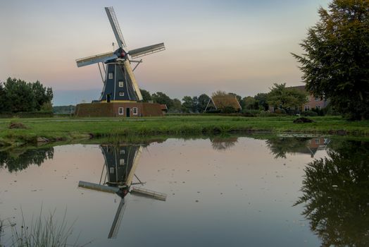 Historic corn mill called The Bataaf in Winterswijk in the evening reflecting in the nearby pond
