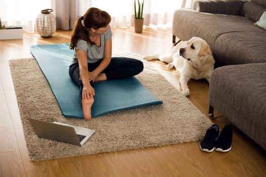 Shot of a woman doing exercise at home with her dog