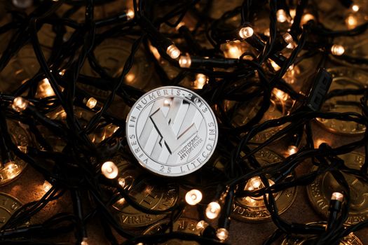 Digital currency physical metal Litecoin coin on the christmas lights concept.
