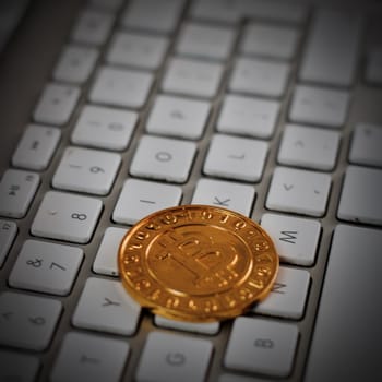 Cryptocurrency physical gold bitcoin coin on the white keyboard.