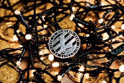 Digital currency physical metal Litecoin coin on the christmas lights concept.