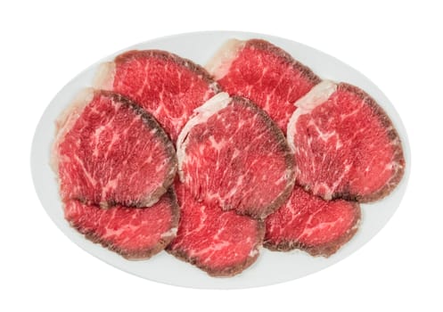 Top view of some raw beef fillets on a plate with  white background