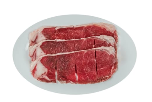 Top view of some raw beef fillets on a plate with  white background