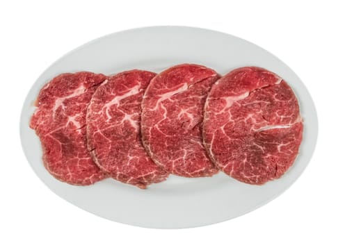 Top view of some raw beef fillets on a plate with  white background