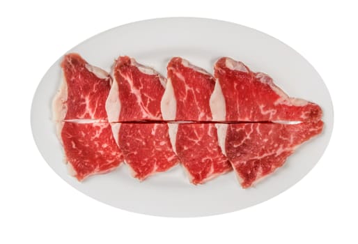 Top view of some raw beef fillets on a plate with  white background