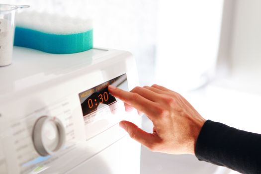 Close up of man hand choosing program for washing machine