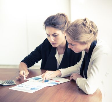 Business women pointing at diagrams discussing financial reports at workplace