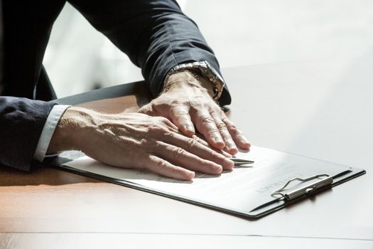 Close-up of businessman keeping hands on contract