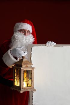 Santa Claus with lantern holding vintage paper billboard with copy space for text