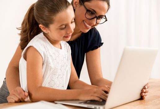 Young mother helping her daughter with homework at home