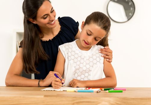 Young mother helping her daughter with homework at home