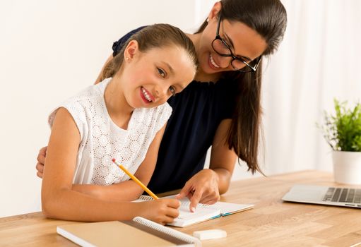 Young mother helping her daughter with homework at home