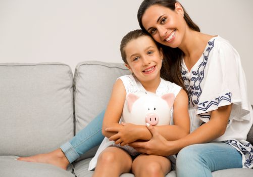 Mother and daughter with a piggy bank for her future savings