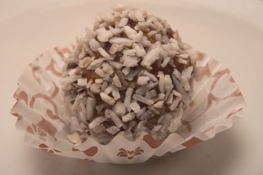 One small sweet round decert made from chocolate, covered with white coconut shavings placed in paper wrapper
