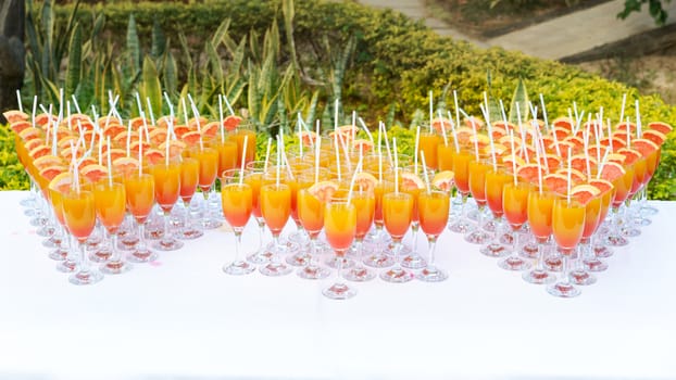 Orange juice cocktail in a flute glasses and slice of fresh orange with draw on white table,Party outdoor.