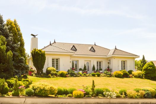 Large white house with two porticos and a beautiful flower garden