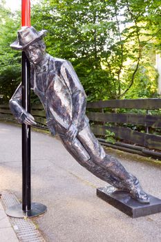 A bronze statue depicting a drunken man standing at a pole