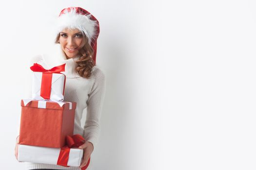 Young woman in Santa hat holding her Christmas gifts