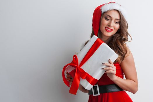 Excited surprised woman in red santa claus outfit holding Christmas present