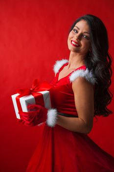 Beautiful woman wearing santa claus costume with gift