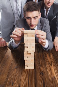 Business people team constructing wooden block tower. Business risk concept