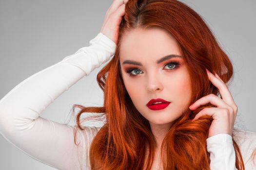 Gorgeous redhead girl with wavy hair beauty studio portrait
