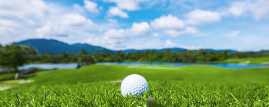 Golf ball on course, beautiful landscape with mountains on background