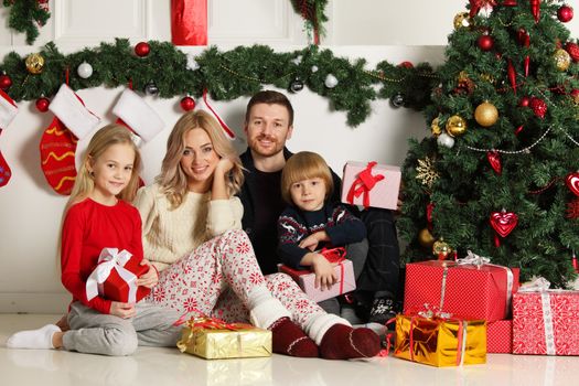 Cheerful family with Christmas gifts sitting near decorated Christmas tree