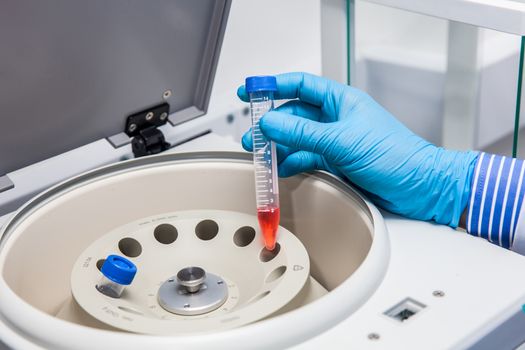 Scientist inserting a tube in a laboratory centrifuge