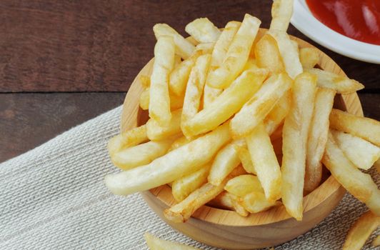 French fries in a bowl on wooden floor.