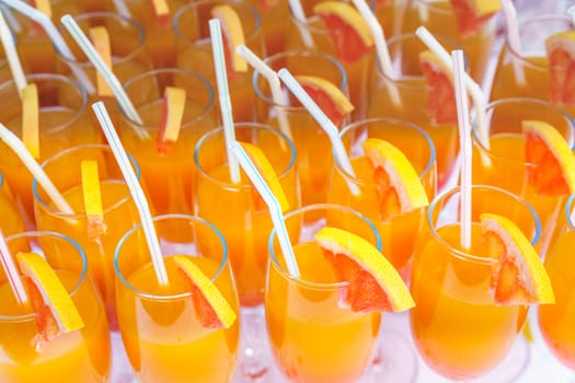 Orange juice cocktail in a flute glasses and slice of fresh orange with draw on white table,closed picture.