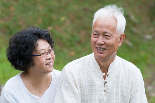 Happy Asian mature couple relaxing at outdoor park on a summer day.