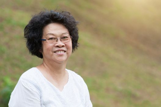 Happy Asian old woman relaxing at outdoor park.