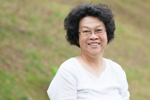 Happy Asian senior woman relaxing at outdoor park.